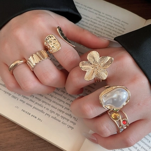 Detailed close-up of stacked gold rings with pearls and gemstones on a vintage book