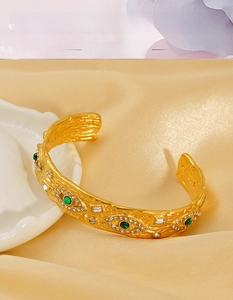 Macro shot of gold hammered stainless steel bangle with malachite evil eye details