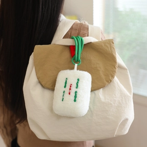 Plush mahjong keychain charm in sparrow pattern attached to a white canvas tote bag