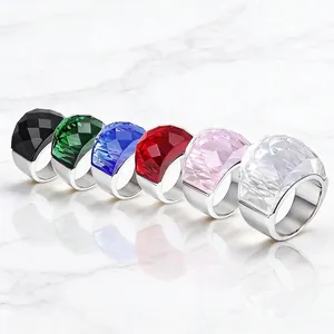 Set of minimalist stainless steel rings with large faceted colorful crystals on marble