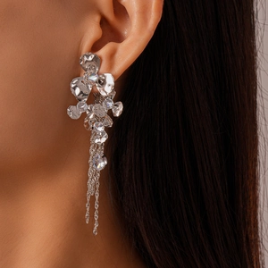 Close-up of silver flower drop earrings with zircon inlay and long tassel fringe chains