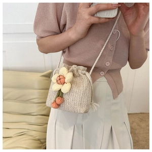 Dettaglio ravvicinato di una mini borsa a secchiello in paglia con fiore e coulisse