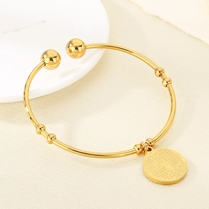 Detail of 18K gold-plated open bangle with engraved religious cross pendant and scripture