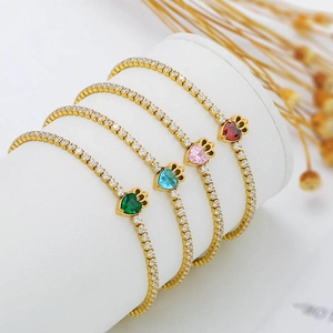 Detail of four gold plated heart zircon bracelets displayed on a white cylindrical stand