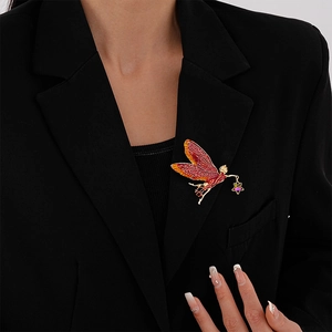 Detail of red enamel fairy brooch with gold trim and purple star jewel on a black suit