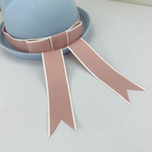 Detail of light blue wool felt hat featuring pink ribbon bow and swallowtail streamers