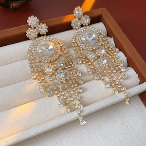 Dettaglio di orecchini vintage dorati con nappe e strass scintillanti in una scatola di velluto