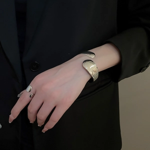 Close-up of a silver liquid metal minimalist open bangle and ring set on a black suit