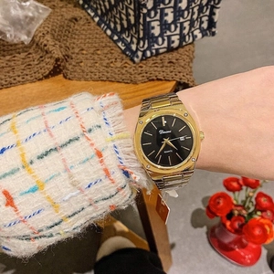 Close-up of golden metal watch with black dial and date display worn on a wrist