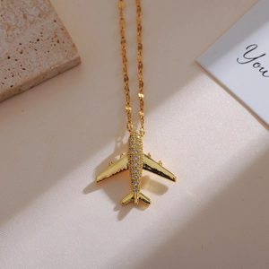 Detailed view of a gold aircraft pendant necklace with sparkling pavé cubic zirconia
