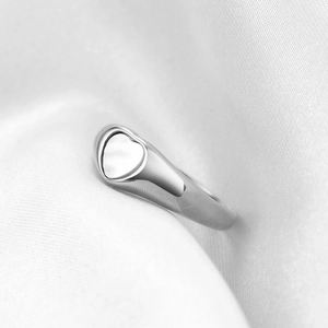 Minimalist silver heart signet ring made of stainless steel on white silk background