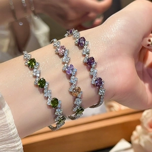 Close-up of elegant silver bracelets set with colorful gemstones and sparkling zircons