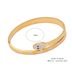 Detailed macro view of gold-plated snake-shaped bracelet with cubic zirconia and oily eyes