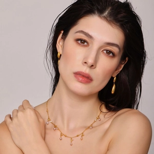 Elegant gold teardrop earrings and pearl necklace set shown on a model in studio