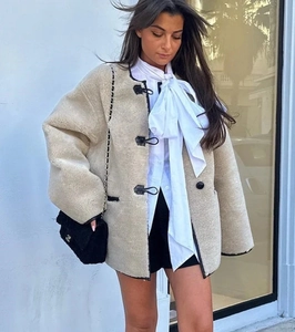 Gros plan sur la veste en polaire beige avec liseré en cuir noir et boutons en corne