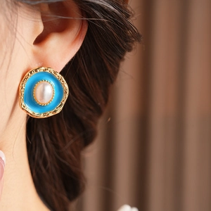 Detail of vintage gold hammered earring with blue enamel and pearl on model's ear