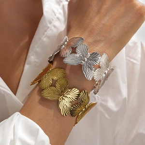 Detail of metal butterfly cuffs showing intricate radial texture in gold and silver