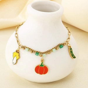 Détail d'une chaîne dorée à double rangée avec charms émaillés champignon et citrouille