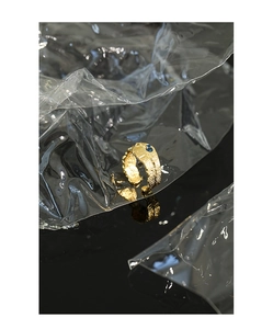 Detail of gold lava texture ring with blue gemstones on a black reflective surface