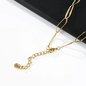 Detail of golden paperclip chain necklace with lobster clasp and round pendant extension