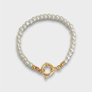 Detailed macro of white round pearls featuring a large gold vacuum-plated spring clasp