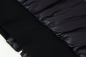 Detailed macro view of black glossy quilted fabric and ribbed knit cuffs on this winter coat