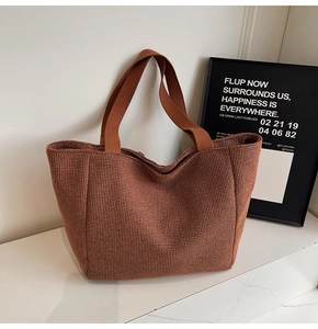 Detail shot of brown woven tweed tote bag texture and fabric handle on marble desk