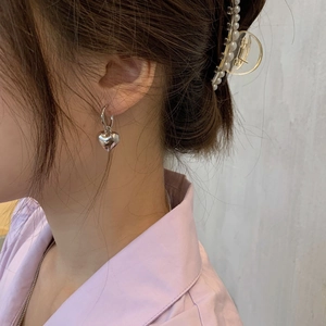 Elegante Frau mit silbernen Herz-Ohrhängern und einer Haarspange mit weißen Perlen