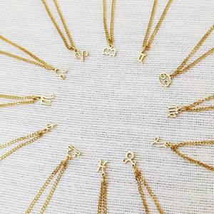 Arrangement of twelve gold zodiac sign necklaces with minimalist hollow line pendants