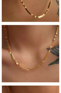 Detailed view of a gold-plated stainless steel twisted blade snake chain on a model's neck
