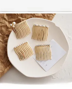 Detail of four golden wave combs with faux pearls and rhinestones on a white tray