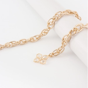 Detail of gold metal waist chain featuring a sparkling flower pendant and textured links