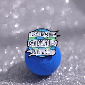 Enamel earth pin badge with 'Destroy the Patriarchy Not the Planet' ribbon text