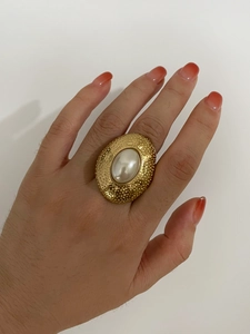 Detailed view of vintage gold ring with hammered texture and oval pearl inlay