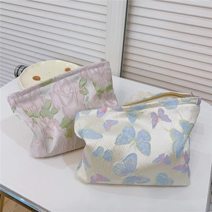 Detail of floral and butterfly jacquard fabric texture on zipper makeup bags