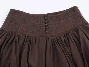 Détail d'une jupe midi marron foncé avec smocks élastiques et boutons recouverts de tissu