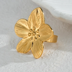 Macro shot of a golden flower ring with detailed radial textures on stone background