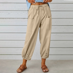 Dettaglio dei pantaloni in lino kaki con vita elastica a coulisse e bottoni laterali