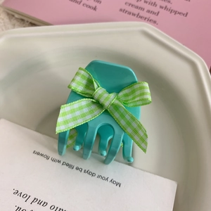 Detailed shot of mint green hair claw clip with a green checkered fabric ribbon bow