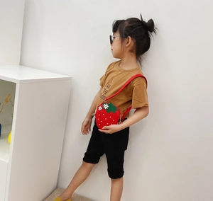 Detailed side view of a red strawberry shaped shoulder bag with pearls for little girls
