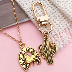 Ensemble collier fer à cheval doré et porte-clés cactus en métal poli sur fond rose