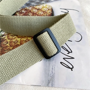 Gros plan détaillé de la bandoulière en toile vert clair avec boucle noire réglable