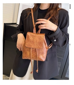 Detail of vintage brown textured leather backpack with drawstring and flap closure