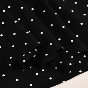 Detail von schwarz-weiß gepunktetem Chiffonstoff mit glatter Textur und weichen Falten