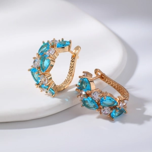 Détail macro de créoles dorées avec zircons marquise bleus et zircons ronds blancs