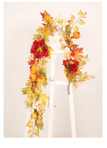 Detail of autumn wreath with pumpkins and dahlia hanging on a white easel
