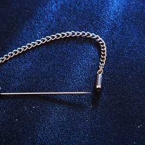 Silver sunflower stick pin with metal tassel chains on elegant dark blue background