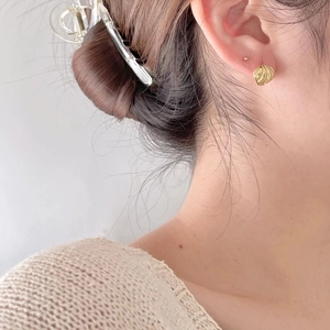 Close-up of golden spiral texture stud earrings on model for a vintage aesthetic
