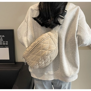 Beige quilted crossbody chest bag worn over a grey sweatshirt showing the back view