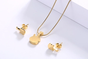 Detail view of a gold guitar jewelry set including necklace and studs on white background